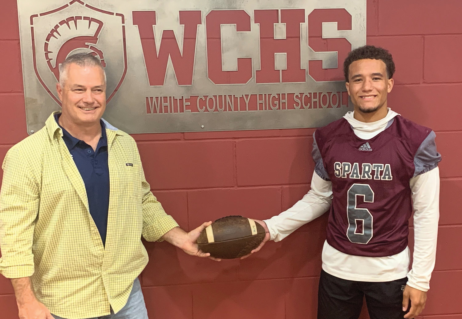 Former White County football Warrior Dewayne Marcus hands off the football to Malaki Dowell. Marcus had set the single season rushing record of 1,500 yards, in 1983. Dowell broke that record this past football season with a total of 2,029 yards.